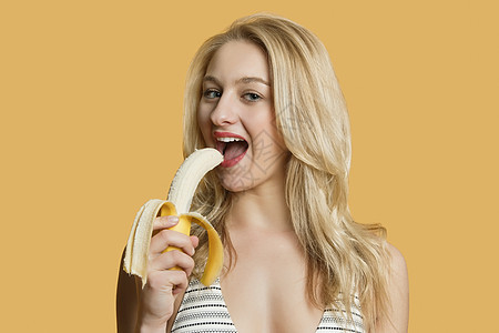 一个美丽的金发美女的肖像 以彩色背景吃香蕉图片