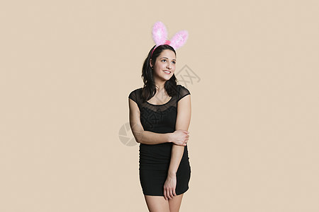 身穿兔子耳朵的快乐年轻女子 对彩色背景视而不见图片