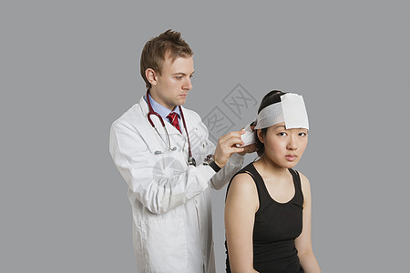 女性病人身上佩戴绷带的医生给头部包上绷带的肖像图片