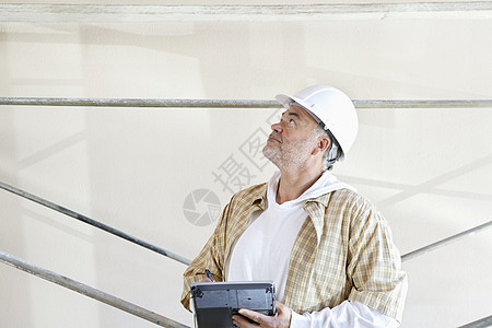 网上装修男性建筑师在数字平板上做笔记 同时查看建筑工地背景