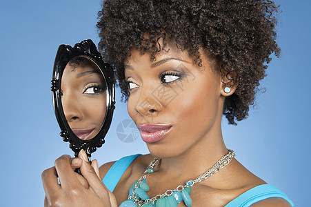 美籍非裔女性透过彩色背景反照镜看自己的近身照片图片