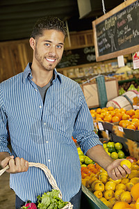 英俊青年男子在市场上买水果的肖像图片