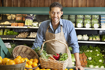水果蔬菜超市一个快乐的年轻销售员 与蔬菜篮子在超市的肖像背景