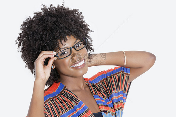 身着非洲印刷服装 戴灰色眼镜的女青年肖像 在灰色背景上穿戴眼镜彩色成人影棚头发种族卷发女性成年短发微笑图片