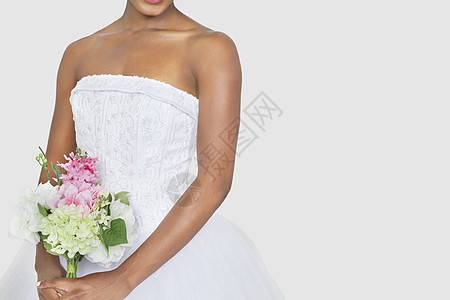 在灰色背景上拿着花束的新娘的中产体仪式白色婚礼影棚婚纱结婚典礼成年双手女性衣服图片