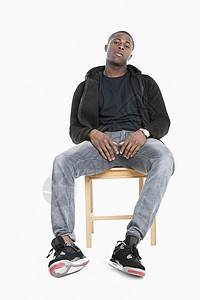 在灰色背景上坐在椅子上的 非裔美国人男子的潮流肖像图片