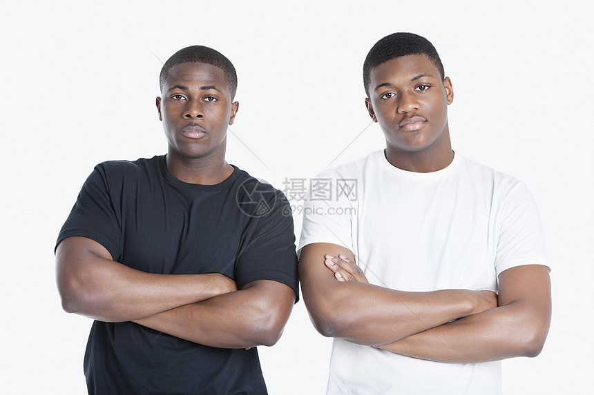 两名非洲裔美国人男性朋友手持双臂穿过灰色背景的肖像图片