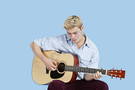 年轻人在蓝背景下弹吉他图片