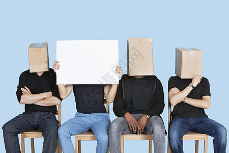 男子拿着空白纸板 有男性朋友面罩满箱蓝背景的黑盒的男人图片
