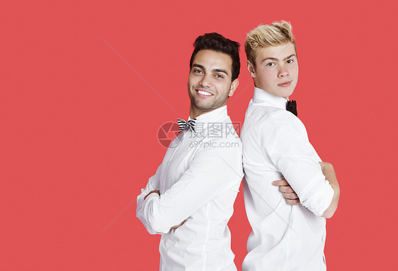 红色背景下两个身着正装的快乐男性朋友背靠背站着的画像图片