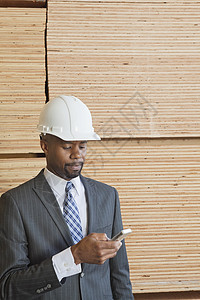 非裔美国男工程师使用手机 用堆叠的木木木木板作为背景图片