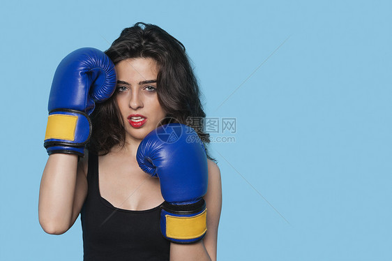 一名身穿蓝底拳击手套的侵略性年轻女子的肖像化妆品背景彩色红色影棚口红体育蓝色器材拳击手图片