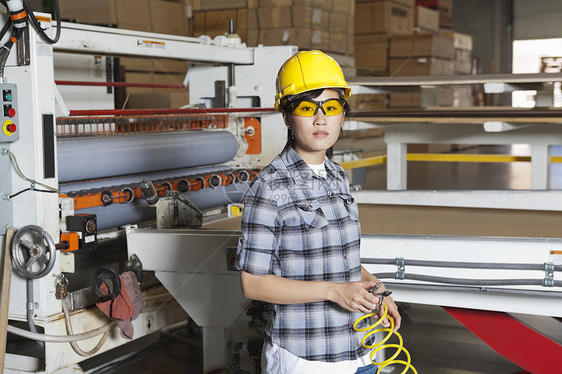 一名亚洲女性工业工人的肖像 她拿着带背景机器的铁丝网图片