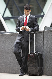 印度青年商务人士 用手机携带行李袋的手提电话图片