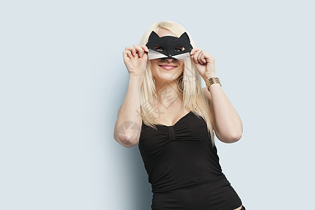 一名年轻女性在浅蓝色背景上戴眼罩的肖像图片