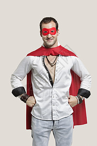 穿着超级英雄服装的年轻男子肖像 手站在灰色背景的臀部站立图片