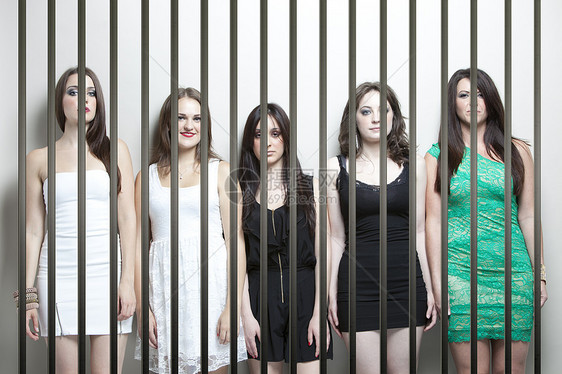 5名女青年站在监狱牢房后面并肩站立的肖像图片