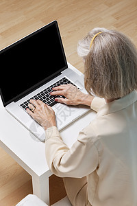 年长妇女在家里用笔记本电脑在网上冲浪图片