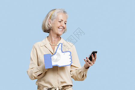 拥有手机的高级女性 假装像蓝背景上的按键一样图片