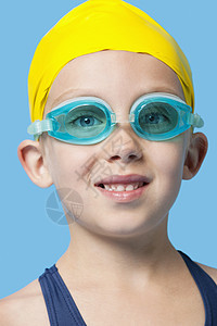 一个穿着泳帽和护目镜的年轻快乐女孩 蓝背景贴近脸部肖像图片