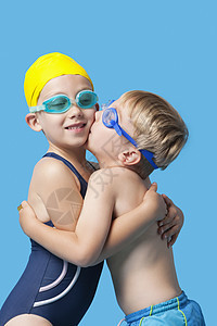 穿着游泳服的年青兄弟姐妹拥抱和接吻蓝底泳镜兄弟男生青年游泳者童年游泳衣运动服女性姐姐图片
