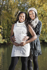 年轻孕妇与女性朋友在公园中度过优质时间的少女肖像;图片