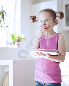 年轻女孩在厨房吃蛋糕房间食品贪婪衣服孩子青年童年粉色食物表情图片
