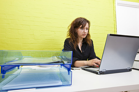 白种女青年在办公桌上用笔记本电脑工作西装衣服实习房间表情商界屏幕成人桌子女士图片