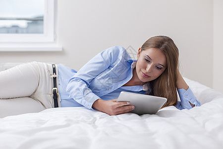 在床上使用平板电脑的漂亮女美女休息场景黑发成人阅读技术家具女性操作双腿图片
