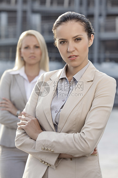 充满自信的年轻女商务人士与背景中的女性同事的一面形象员工业务正装焦点合作生意人两个人西装团结商界图片