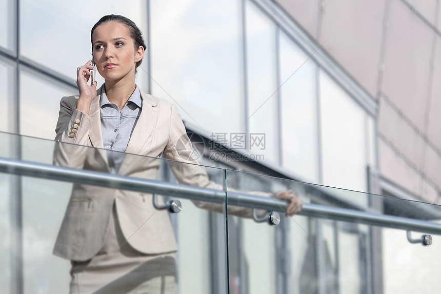 自信的年轻女商务人士在办公室阳台使用手机图片