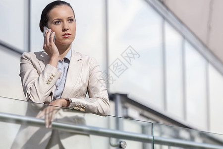 严重的年轻女商务人士在办公室栏杆上使用智能电话商业职业高管生意人业务员工手机通讯西装办公楼图片
