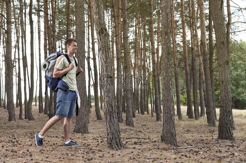 带背背背包在森林中行走的全身青年男子图片