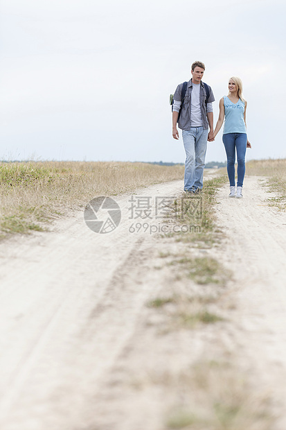整个年幼徒步旅行夫妇在田野的足迹上行走图片