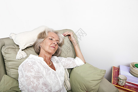 在家坐在扶手椅上睡觉的年老疲累妇女图片