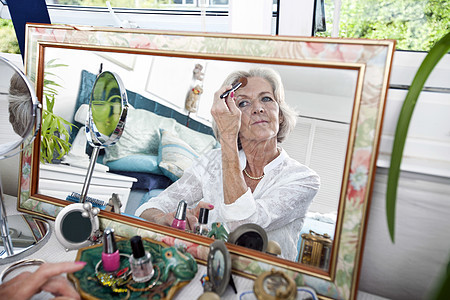 年长妇女在家里打脸的镜像反射图片