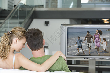 年轻夫妇在客厅看电视的后视景闲暇房子成人屏幕休闲娱乐场景男子团结沙发图片