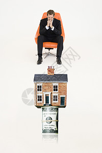 钱 卷房顶上挂着一卷法案 被收买的商务人士坐在椅子上代表昂贵地产花费屋主纸币人士房地产经济影棚男性安全抵押背景