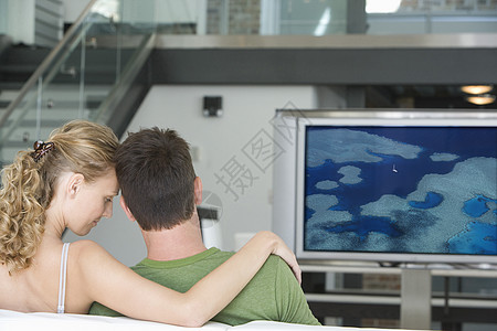 年轻夫妇在客厅看电视的后视景团结家具男性沙发电影家庭屏幕房子两个人休闲图片