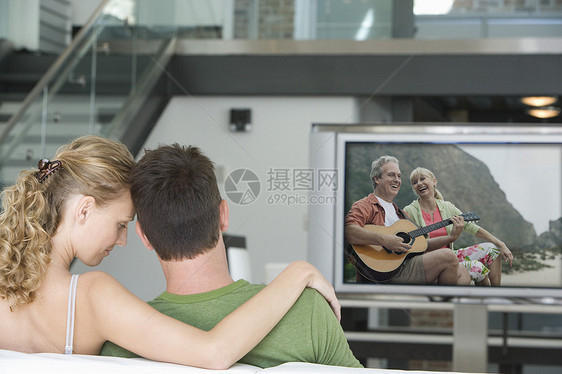 年轻夫妇在客厅看电视的后视景沙发服装男士场景电视成年闲暇感情休闲娱乐图片