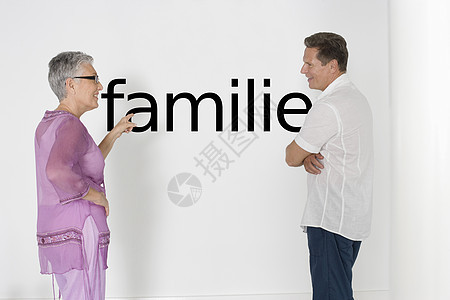 讨论家庭问题与白墙对立的一对夫妇 用德语文本“Familie”来讨论家庭问题图片