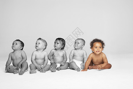 婴儿女孩和其他婴儿一起在地板上看图片