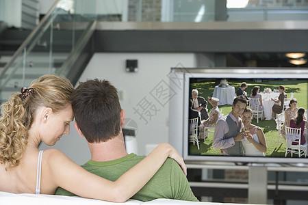 年轻夫妇在客厅看电视的后视景电视成人男性成年团结闲暇休闲头肩感情家具图片