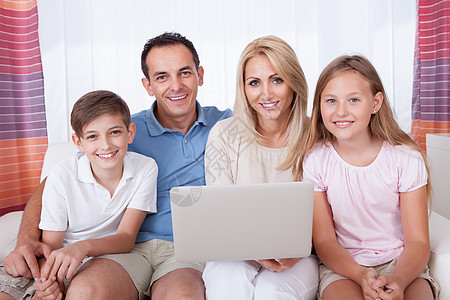 使用笔记本电脑的幸福家庭女孩们拥抱亲热父亲技术中年人喜悦女性男性父母图片