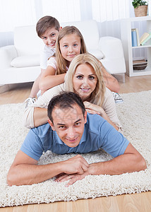 幸福的家庭在客厅的地毯上躺着图片