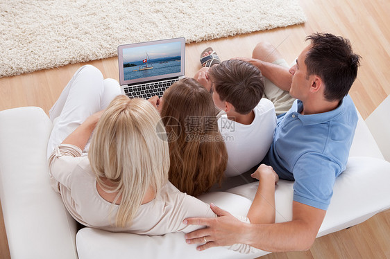 家庭快乐坐在用笔记本电脑的索法上母亲拥抱男人成人男孩们互联网高架父亲亲热男性图片