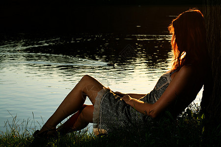 女孩坐在森林河岸上的女孩乡村假期女士女性草地农村国家树木银行娱乐图片