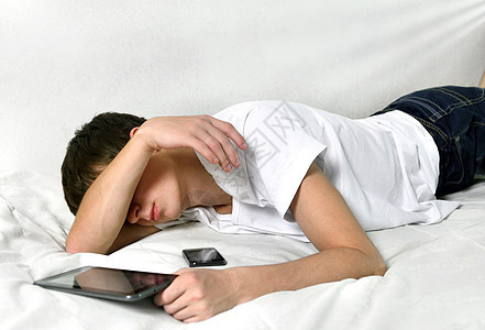 年轻人用平板电脑睡觉被单轨枕瞌睡男性青少年房间互联网沙发说谎睡眠图片