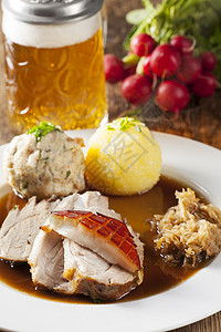 巴伐利亚烤猪肉加啤酒萝卜木头桌子食物肉汁脆皮饺子土豆噼啪紧缩图片