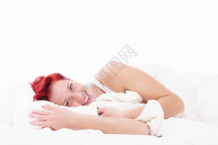 床上快乐的女人成人毯子女性女孩乐趣微笑红色白色枕头说谎图片